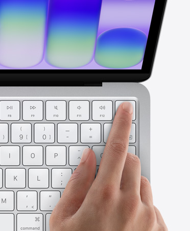 MacBook Neo, argent, doigt d’une personne sur le capteur Touch ID dans le coin supérieur droit du clavier