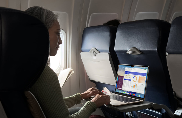 Una persona sentada en un asiento de avión trabaja con su MacBook Air