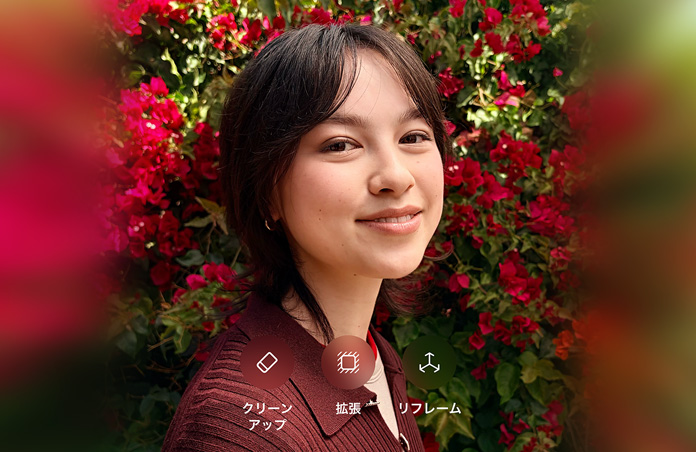 茶髪の人物が微笑んでいる写真。茶色のセーターを着て、赤い花に囲まれている。写真上に表示されている「Clean Up」「Extend」「Reframe」のオプションを使ったAIによる写真編集を示している