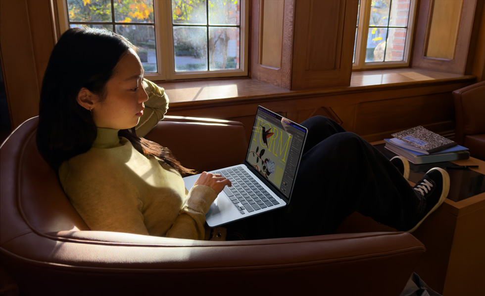Koltukta oturan ve MacBook Air kullanan bir kişi