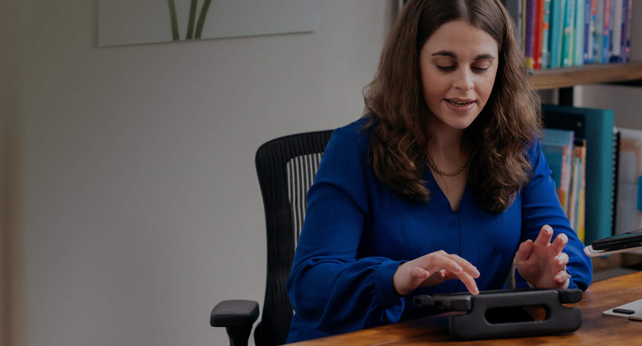 Foto de Jordyn Zimmerman, Apple Distinguished Educator y defensora de las personas con discapacidad, sentada en un escritorio escribiendo en la pantalla de un iPad