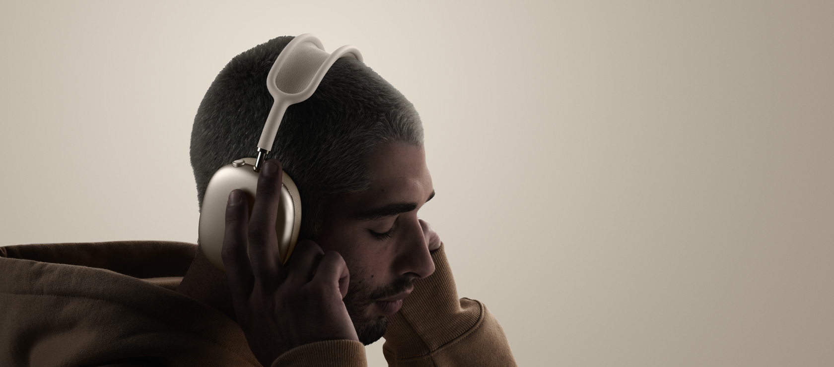 Človek má nasadené slúchadlá AirPods Max 2, pohľad zboku, dotýka sa náušníkov
