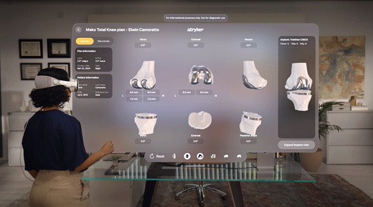 Une chirurgienne portant un Apple Vision Pro interagit avec la représentation 3D des os et jointures d’un genou, auxquels sont fixées des pièces métalliques