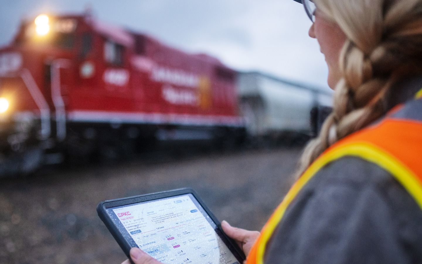 A railway worker assesses train schedules on iPad while standing in the train depot