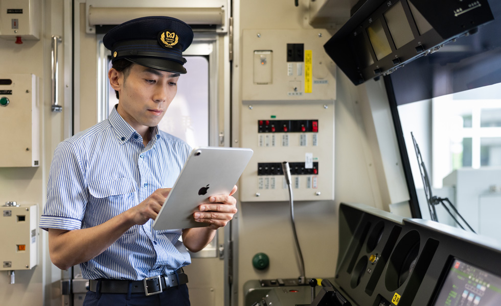 En T-banefører bruker iPad mens han står i det opplyste førerhuset til T-banen.