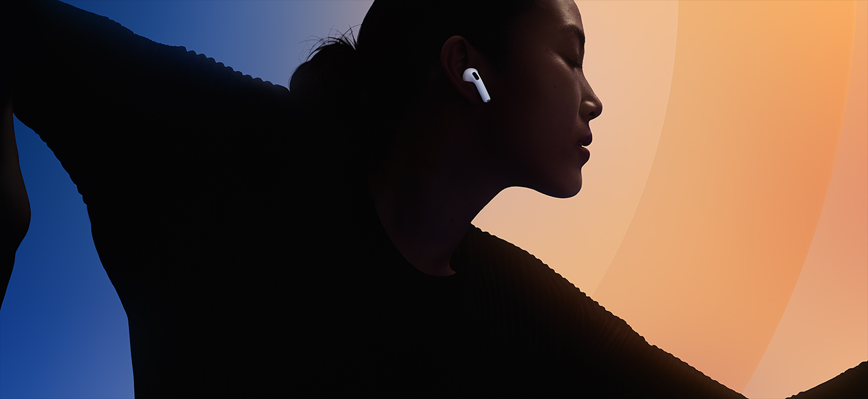 AirPods 5, white colour, worn in the ear, person silhouetted against multi-colour background